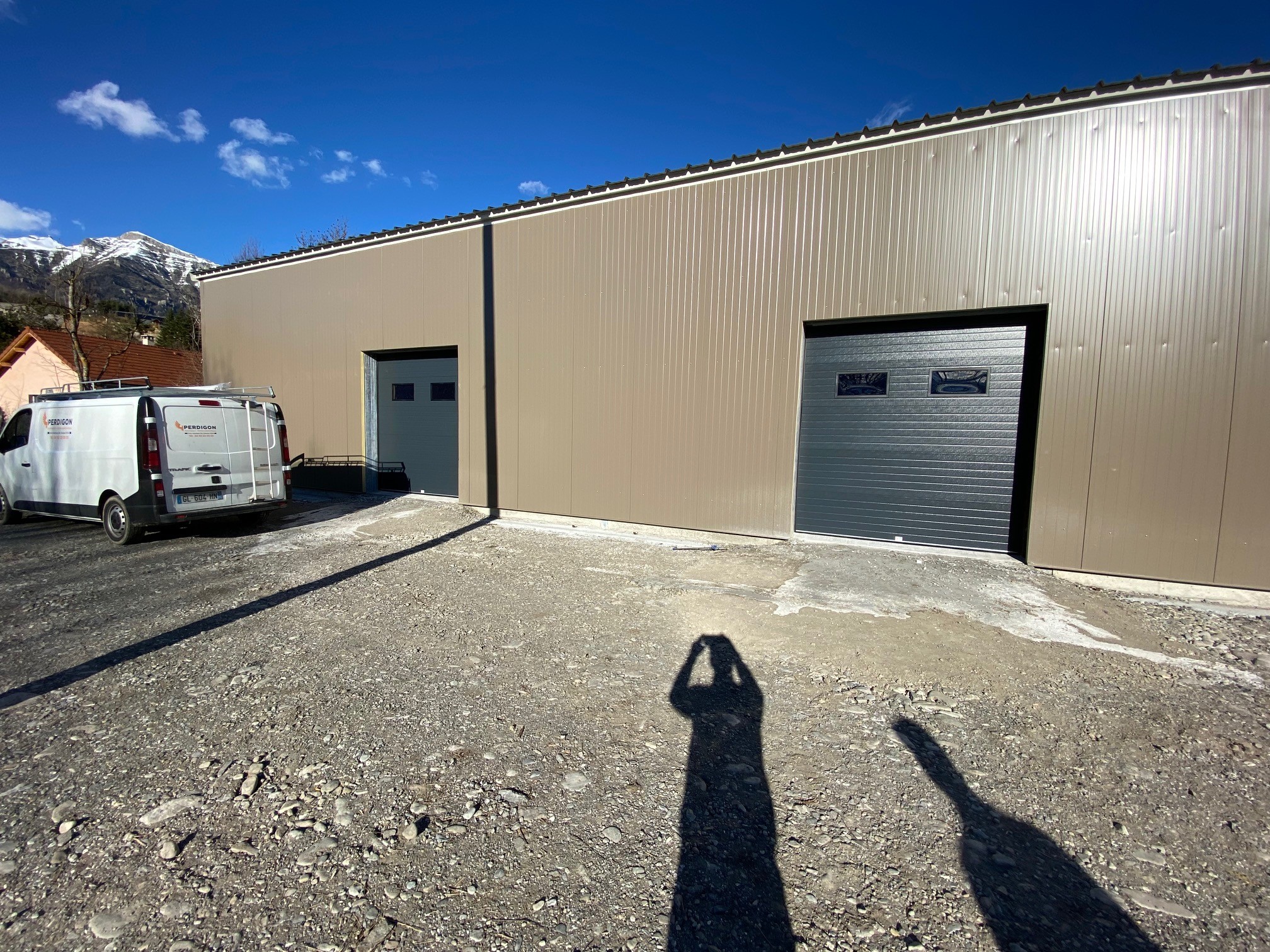 Un homme prend en photo des portes de garage vue de l'extérieur suite à l'installation de portes de garages chez un particulier